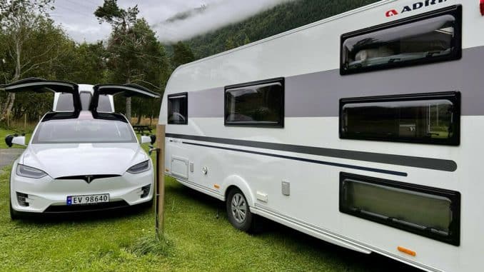 E-Auto-auf-Campingplatz E-Auto neben Caravan auf Campingplatz
