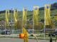 Gelbe Fahnen mit Logo des TCS auf einem Parkplatz. Im Vordergrund gelbe Blumen, im Hintergrund grüne Hügel.