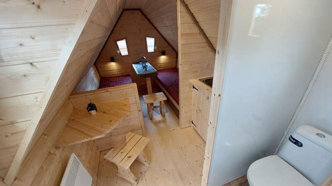 Schlaf- und Wohnbereich eines Mobilheims aus Holz mit starker Dachschräge