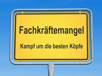 Straßenschild vor blauem Himmel mit Aufschrift: Fachkräftemangel Kampf um die besten Köpfe.