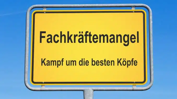 Straßenschild vor blauem Himmel mit Aufschrift: Fachkräftemangel Kampf um die besten Köpfe.