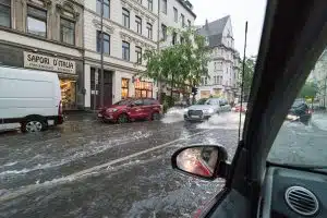 Blick aus Auto auf Straße mit Hochwasser in einer Innenstadt.