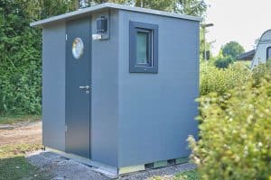 Graues, kleines Privatbad von außen auf einem Campingplatz.