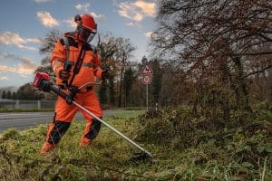 Mann in Schutzkleidung mit Kress Freischneider in einer Wiese.