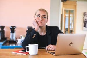 Boreout-Syndrom: Langeweile am Arbeitsplatz. Eine gelangweilte Frau am Laptop im Büro.