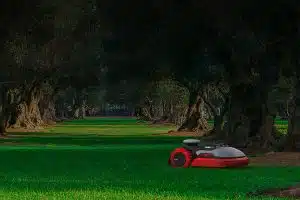 Smarter Mähroboter von Kress in einem Park umgeben von Bäumen.