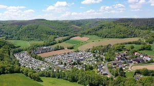 Luftaufnahme eines Campingplatzes in hügeliger, bewaldeter Landschaft