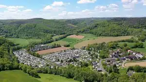 Luftaufnahme eines Campingplatzes in hügeliger, bewaldeter Landschaft