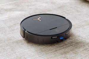 Autonomer Staubsaugerroboter in schwarz auf einem Teppichboden.