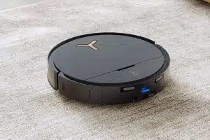 Autonomer Staubsaugerroboter in schwarz auf einem Teppichboden.