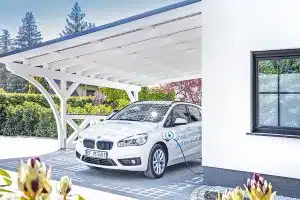 Überdachung mit Solar darüber an einem Haus angebaut und Auto das darunter lädt.