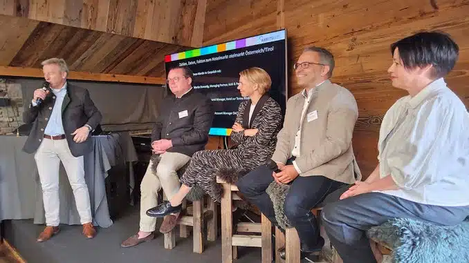 Redner vom Arbeitskreis Hotelimmobilien auf der Bühne mit Präsentation auf Bildschirm.