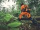 Mann im Wald mit orangener Schutzkleidung von Stihl.