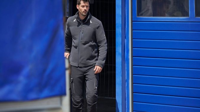 Mann in Berufskleidung geht aus einer Tür.