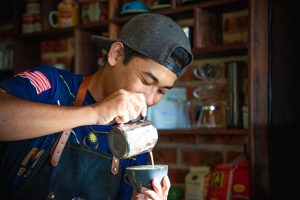 Ein Barista gießt Milchschaum in eine Tasse